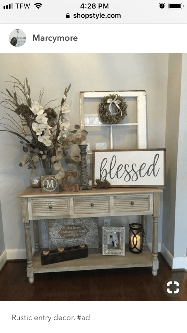 Rustic entryway table decorated with white flowers, a 'blessed' sign, and a vintage window frame.
