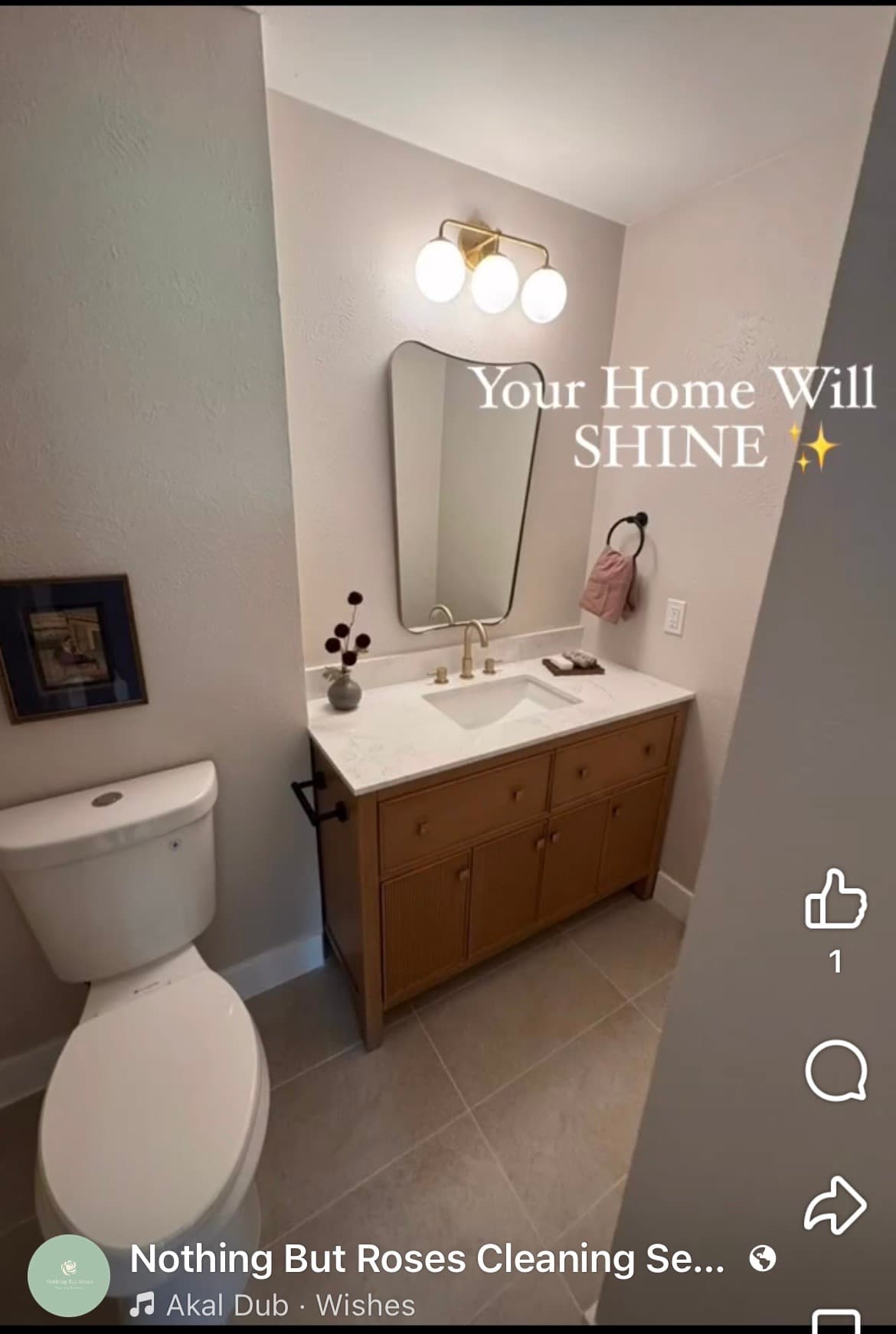 Clean bathroom featuring a wooden vanity, marble countertop, asymmetrical gold mirror, and a white toilet.